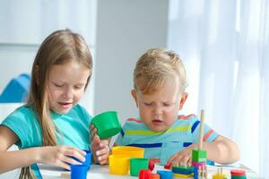 irmã ajuda pequeno irmão para montar a pirâmide. educacional lógico brinquedos para crianças. montessori jogos para criança desenvolvimento. foto