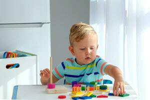 pequeno Garoto 2 anos velho é reproduziu com uma de madeira pirâmide. educacional lógica brinquedos para crianças. montessori jogos para criança desenvolvimento. foto