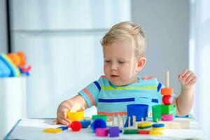 pequeno Garoto 2 anos velho é reproduziu com uma cores brinquedos. educacional lógica brinquedos para crianças. montessori jogos para criança desenvolvimento. foto