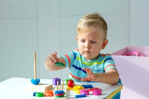 pequeno Garoto 2 anos velho é reproduziu com uma de madeira pirâmide. educacional lógica brinquedos para crianças. montessori jogos para criança desenvolvimento. foto