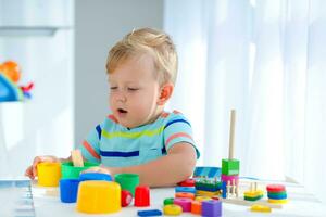 pequeno Garoto 2 anos velho é reproduziu com uma cores brinquedos. educacional lógica brinquedos para crianças. montessori jogos para criança desenvolvimento. foto