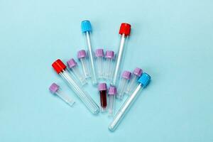 uma teste tubo preenchidas com sangue entre muitos esvaziar teste tubos em uma azul fundo foto