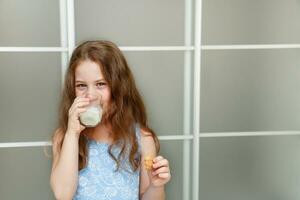 pequeno menina comendo biscoitos com leite foto