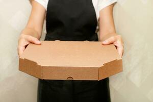 uma mulher cafeteria trabalhador detém Fora uma caixa com pronto pizza foto
