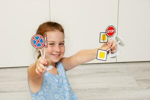 fofa pequeno menina segurando brinquedo estrada sinais dentro dela mãos foto