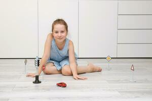 fofa pequeno menina jogando às casa em a chão com uma máquina de escrever, estrada sinais e tráfego luzes foto