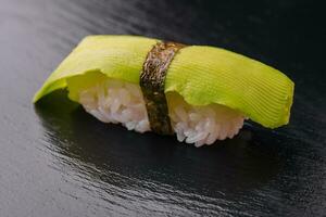 japonês Sushi conjunto com abacate em Preto madeira foto