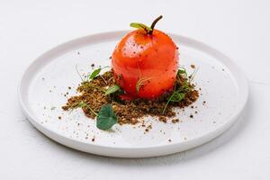 incomum sobremesa dentro a forma do uma tomate em uma branco prato foto