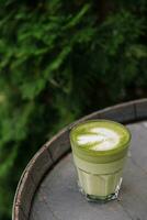 matcha café com leite verde leite espuma copo em madeira barril foto