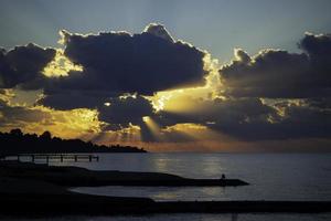 paisagem marinha com um pôr do sol brilhante e raios através das nuvens foto