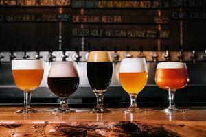 diferente tipos do construir Cerveja dentro óculos em mesa dentro bar interior dentro luz do dia foto