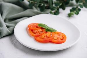 fatiado vermelho tomates e manjericão folhas foto