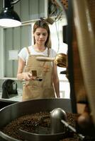 retrato do uma jovem mulher trabalhando com uma café torrador máquina foto