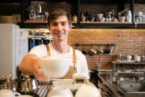 retrato do uma sorridente masculino barista segurando uma copo do café foto