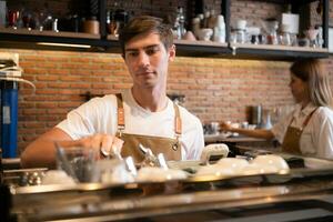 barista trabalhando dentro cafeteria. retrato do jovem masculino barista em pé atrás contador dentro café fazer compras. foto