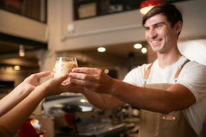 barista segurando uma vidro do frio café com leite café dentro dele mãos para cliente foto