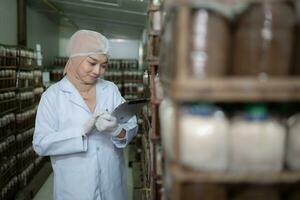 jovem ásia muçulmano fêmea cientista fazendo pesquisa às uma cogumelo fábrica, examinando cogumelo fermento agente dentro uma estéril e com temperatura controlada sala. foto