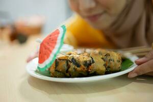 muçulmano menina comendo cogumelo Sushi às a restaurante. seletivo foco em Sushi foto