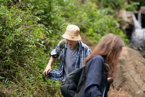 grupo do amigo em uma ensolarado dia dentro a floresta jovem grupo caminhante com mochila e caminhada postes foto