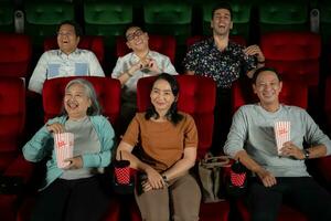 grupo do ásia Senior amigos assistindo comédia filme e rir às a cinema com Pipoca foto