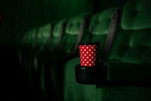 cinema auditório com verde assentos e uma vermelho copo do beber foto