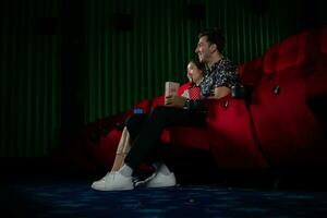 jovem homem e mulher assistindo filme dentro cinema, sentado em vermelho assentos foto