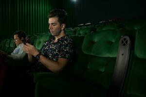 jovem casal assistindo filme dentro cinema, sentado em a verde assentos. foto