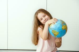 feliz menina segurando uma globo dentro dela mãos foto