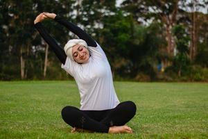 mulher agradável em hijab e roupas esportivas, fazendo ioga e alongamento. foto