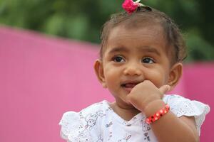 fofa indiano bebê menina sorridente em Rosa fundo foto