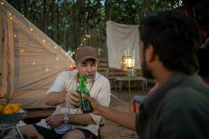 grupos de turistas bebendo cerveja-álcool e tocando violão junto com diversão e felicidade no verão enquanto acampam foto