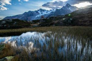 uma montanha alcance é refletido dentro uma pequeno lago foto