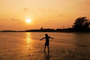 uma pessoa em pé em a de praia às pôr do sol foto