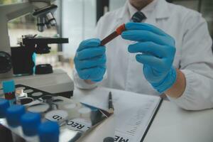 cientista ou médico dentro laboratório casaco trabalhando dentro biotecnológico laboratório, microscópio equipamento para pesquisa com mistura reagentes dentro vidro frasco dentro clínico laboratório. foto