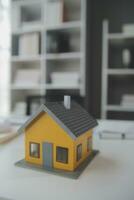 modelo de casa com agente imobiliário e cliente discutindo contrato para comprar casa, seguro ou empréstimo de fundo imobiliário. foto