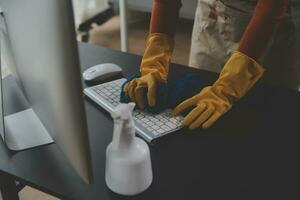 escritório limpeza serviço. zelador pulverização escrivaninha. local de trabalho higiene foto