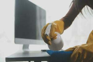 escritório limpeza serviço. zelador pulverização escrivaninha. local de trabalho higiene foto