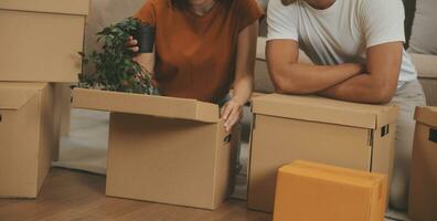 lindo jovem casal dentro amor tendo Diversão desembalar coisas a partir de cartão caixas enquanto comovente dentro juntos dentro seus Novo apartamento foto