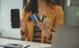 mulheres segurando crédito cartão e usando smartphones às casa.online compras, Internet bancário, loja on-line, pagamento, gastos dinheiro, comércio eletrônico Forma de pagamento às a loja, crédito cartão, conceito foto