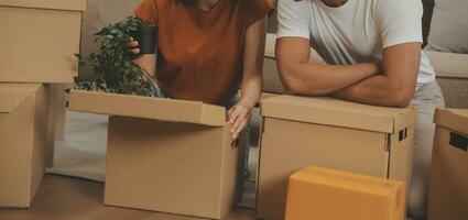 lindo jovem casal dentro amor tendo Diversão desembalar coisas a partir de cartão caixas enquanto comovente dentro juntos dentro seus Novo apartamento foto