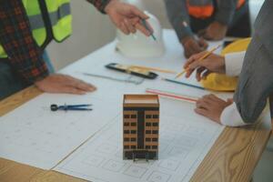 conceito de construção e estrutura de reunião de engenheiro ou arquiteto para projeto trabalhando com parceiros e ferramentas de engenharia na construção de modelo e projeto no local de trabalho, contrato para ambas as empresas. foto