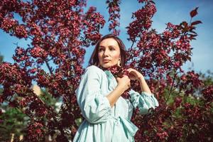 uma jovem está parada no parque sob uma macieira em flor foto