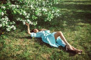 garota deitada no parque na grama sob uma macieira em flor foto