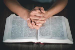 mãos de mulher orando a Deus com a bíblia foto