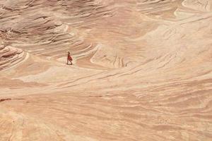 mulher caminhando sobre uma formação rochosa de arenito no deserto foto