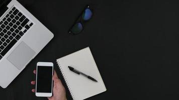 mão com smartphone laptop notebook em fundo preto foto