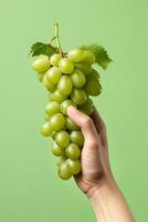 mão segurando verde uvas grupo isolado em verde fundo. ai gerado foto