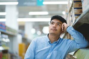 empregados estão asiáticos quem trabalhos Difícil dentro a compras shopping center. costas dor enquanto trabalhando. fadiga, exaustão, estresse a partir de trabalhar. foto