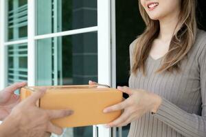 feliz sorridente mulher recebe caixas parcela a partir de correio dentro frente casa. Entrega homem mandar entregar expressar. conectados compras, papel containers, remover, carteiro, Entrega serviço, pacotes foto