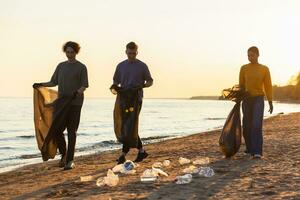 terra dia. voluntários ativistas equipe coleta lixo limpeza do de praia costeiro zona. mulher mans com Lixo dentro lixo saco em oceano costa. de Meio Ambiente conservação costeiro zona limpeza. foto